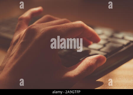 Young human hand is typing on the keyboard, selective focus. Stock Photo