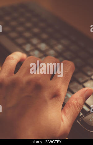 Female hand is typing on the keyboard, selective focus on the finger. Stock Photo