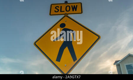 Panorama frame Yellow Slow sign and pedestrian crossing sign against cloudy sky at sunset Stock Photo