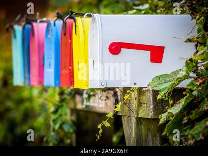 Close up of a row of colorful traditional american letterboxes mounted on a wooden stand, against a ivy background Stock Photo