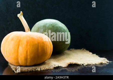 Two green and orange pumpkins on a black background. Copy space. Stock Photo