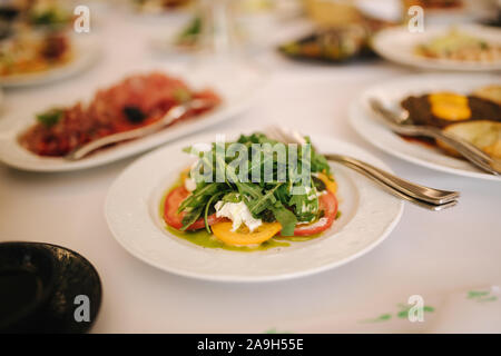 Fresh salad in restaurant on the table. Banquet concapt. Different salads with tomato, arugula, chicken, avocado, parmesan, shrimp. Stock Photo