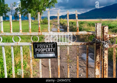 Private Property sign on an old rusty white gate locked with chain and padlock Stock Photo
