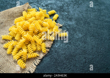 Raw pasta on a transparent square plate on a black background. Copy space. Top view. Stock Photo