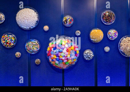 A blue wall with clear, plastic spheres holding objects like, toy cars, macaroni, bows, golf tees, googly eyes, building block, etc. Stock Photo