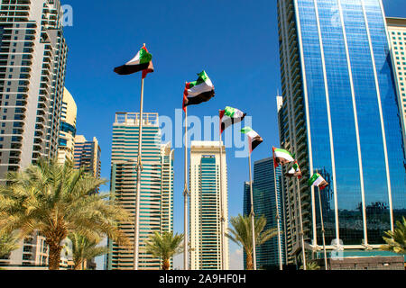 View of Dubai buildings with UAE flags. United Arab Emirates flags waving on blue sky background. Independence day. UAE flags on street. Flag day Stock Photo