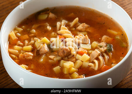 Soup with fusilli, chicken meat and vegetables in a white bowl Stock Photo