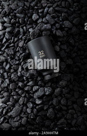 Black matt hex wrench head placed on a stony ground. View from the top. Stock Photo