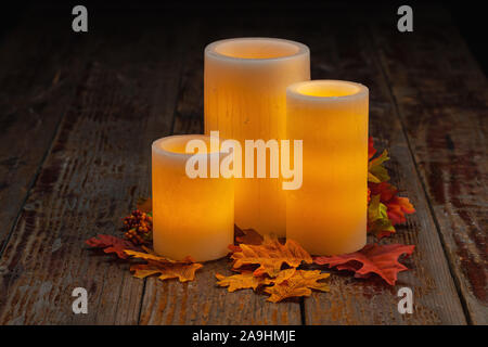 Fall holiday Still life of electric wax candles with fall leaves on wooden tabletop Stock Photo