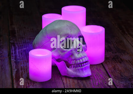Halloween holiday still life of purple electric wax candles and an artificial skull Stock Photo