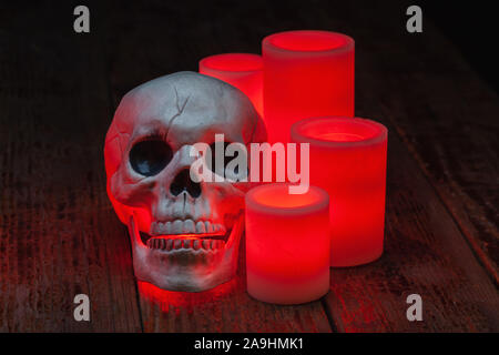 Halloween holiday still life of red electric wax candles and an artificial skull Stock Photo