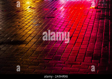 reflection of colored lights on the pavement at night. shine cobbled neon Stock Photo