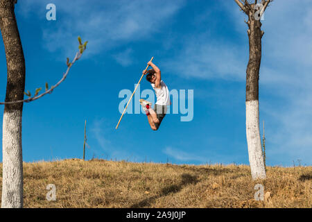 Man jumping with kung-fu staff under the blue sky Stock Photo