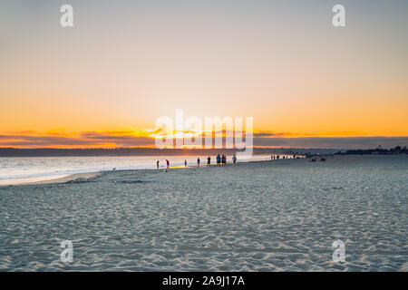 Sunset on the beach. Silhouettes of people on shore at golden hour Stock Photo