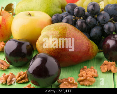 set of fruits on a green wooden table - apples, pears, grapes, plums, walnuts Stock Photo