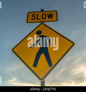 Square frame Yellow Slow sign and pedestrian crossing sign against cloudy sky at sunset Stock Photo