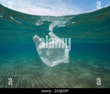 Plastic pollution underwater, a white plastic bag in the sea below water surface Stock Photo