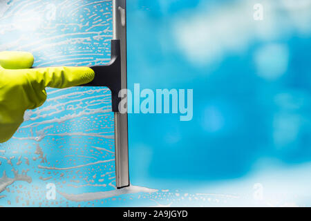Cleaner Wearing Gloves Cleaning Soap Suds From Glass Window With Squeegee Wiper Stock Photo