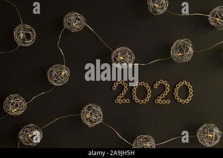 Celebration of New Year 2020. Metallic theme. Beautiful spherical lights, which surround numbers 2020, made from pasta. Trendy concept Stock Photo