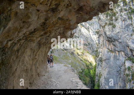 PONCEBOS, SPAIN - APRIL 29, 2017: Couple of Hikers walking along The Cares Trail, one of the most popular trekking paths within the Picos de Europa du Stock Photo