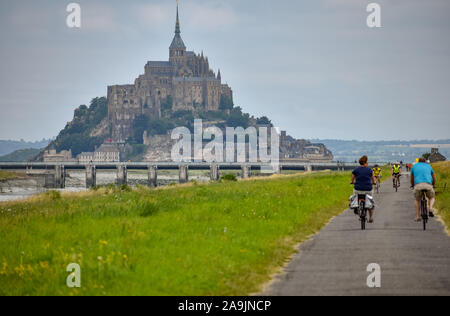 MONT SAINT-MICHEL, FRANCE - JULY 3, 2017: Cyclists go on a summer day to Mont Saint-Michel, one of the most important tourist destinations in French N Stock Photo