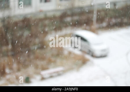 Blurred winter background with snowflakes on the foreground. White snowflakes falling from the sky. Nature seasonal picture. Car covered with snow Stock Photo