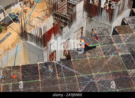 Bangkok, Thailand - November 16, 2019 : Two workers wearing uniforms and helmets are carrying precast concrete slab while working at construction site Stock Photo