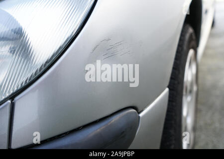 Close up of dent and scratches on side of old silver gray car. Damage from crash accident, parking lot or traffic. Stock Photo