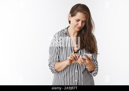 Mother checking messages in smartphone waiting for phonecall, holding mobile, browsing net, looking at screen focused as searching recipe in internet, Stock Photo