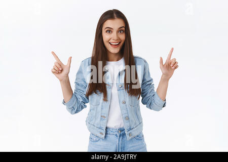 Upbeat, enthusiastic stylish girl in denim jacket, jeans pointing sideways, give two choices, recommend both left and right advertisement, smiling exc Stock Photo