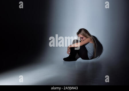 Sad and frightened little girl with bloodshot, bruised eyes sitting scared. Concept of child violence, domestic abuse. Sad, depressed being victim of parents and their agression. Children's rights. Stock Photo