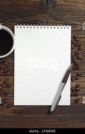 Opened notepad with empty page, pen and cup of hot coffee on table, top view Stock Photo