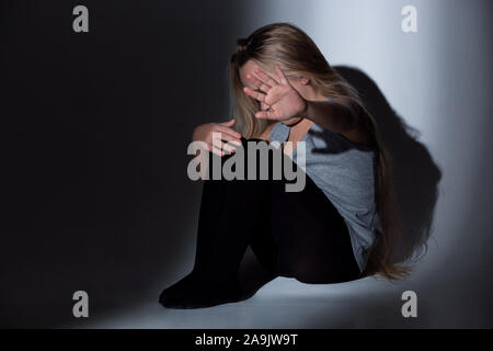 Sad and frightened little girl with bloodshot, bruised eyes sitting scared. Concept of child violence, domestic abuse. Sad, depressed being victim of parents and their agression. Children's rights. Stock Photo