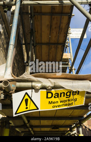 Danger sign Men working overhead on scaffolding Stock Photo