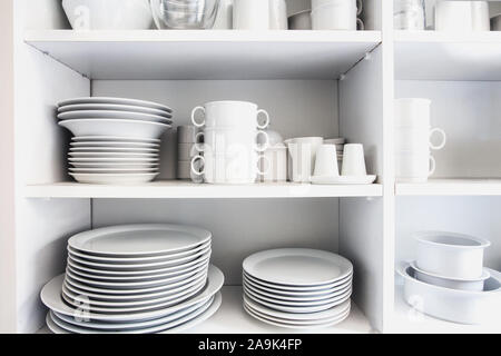 White Cupboard with white crockery in the kitchen, various clean dishes Stock Photo