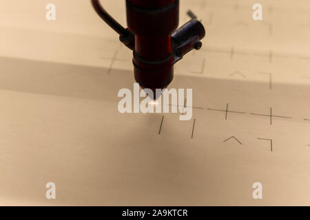 close-up of a flying head of a laser cutting machine, beam burning out grooves in plywood Stock Photo
