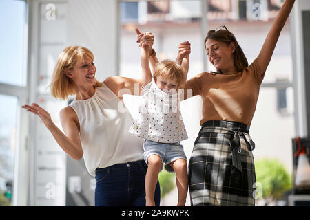 Happy gay mothers  with smiling child girl in store for household Stock Photo