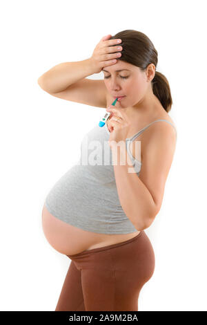 Young pregnant woman checking her temperature using oral thermometer Stock Photo
