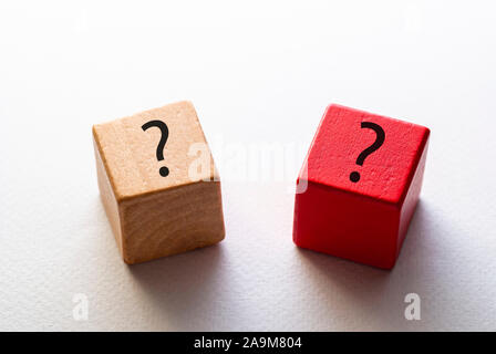 Two wooden dice or toy blocks with question marks , one natural wood and one red, on a white background in a high angle view Stock Photo