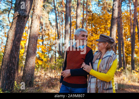 Autumn walk. Senior couple walking in fall park. Happy man and woman talking and relaxing outdoors Stock Photo