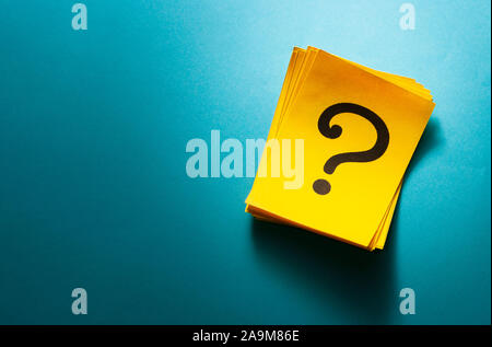 Stack of bright colorful yellow cards with question mark viewed from above on a blue background with copy space Stock Photo