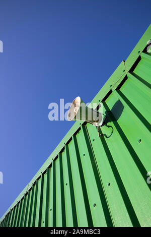 PA public address system speaker fixed to profiled metal clad building Stock Photo
