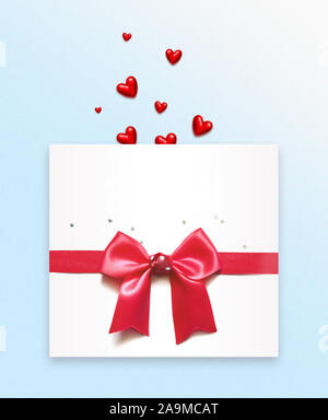 Red hearts and white envelope with red bow on blue background. Stock Photo
