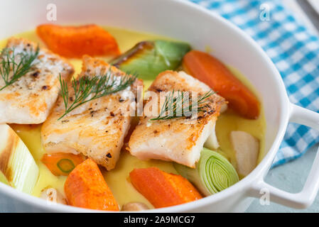 Cod fish baked with vegetables in a lemon sauce. Stock Photo