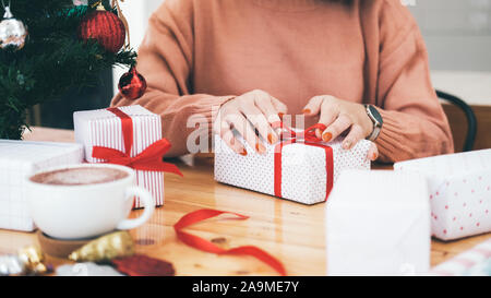 Hands of woman decorating christmas and New Year gift box. Holiday concept. Stock Photo