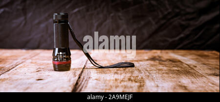 Small pocket LED torch isolated on wooden table Stock Photo
