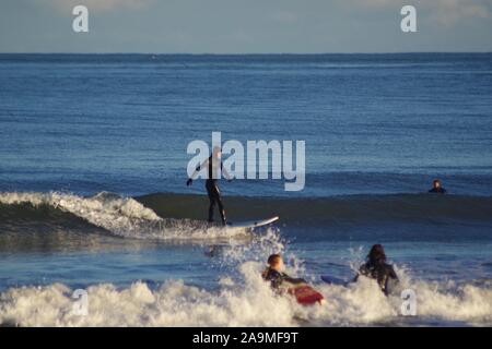 Four Surfers in the North Sea on a Winters Evening. Aberdeen, Scotland, UK. Stock Photo
