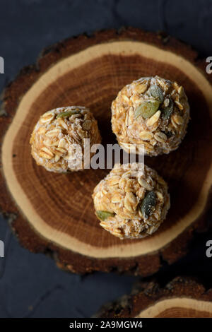 Vegan food concept. Close up of frozen oatmeal energy balls with pumpkin seeds on oak wood slab on black background top view copy space Stock Photo