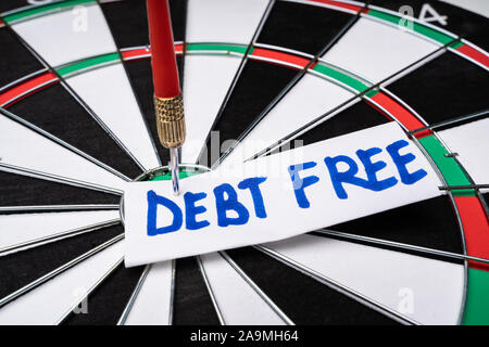 Close-up Of Handwritten Text Debt Free On Notepaper Stuck At The Center Of Dartboard Stock Photo