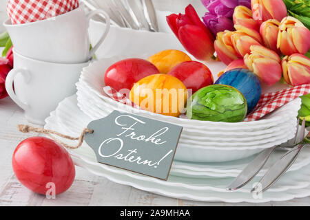 German Happy Easter Easter Easter Decoration Breakfast Table Red Tulips with red Easter Eggs as Background Stock Photo